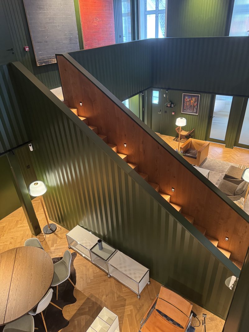 Sett ovenfra fra galleriet: trappa ned i loungen, med et rundt bord og stoler under